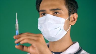 Coronavirus 'a karşı mavi maske takan profesyonel bir kıdemli doktor. Erkek bir laboratuvar teknisyeni enjeksiyon için bir şırınga hazırlıyor COVID-19 aşısı, virüse karşı koruma, yeni normal, salgın