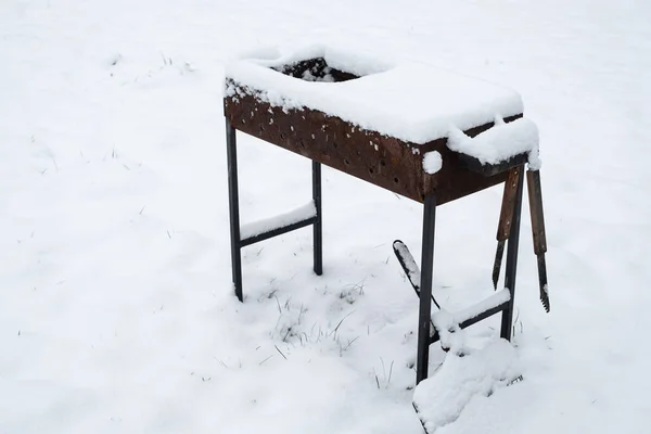 Rusty grill covered with lots of snow. Cold winter weather conditions. Extreme snow. Cool BBQ grill left out under snow.