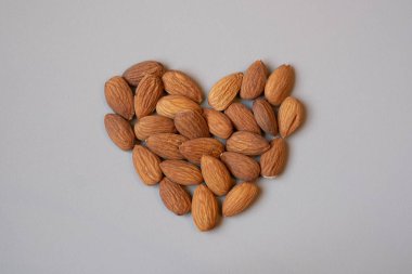Gri arka planda kalp şeklinde bademler. Sağlıklı beslenmeyi severim. Sağlıklı çerez.