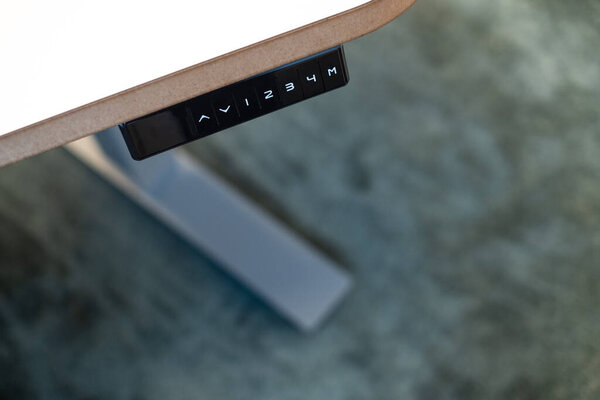 Регулируемый офисный стол с кнопками вверх, вниз и памяти на пульте дистанционного управления. Умный регулируемый по высоте стол или стоячий стол. Современное офисное оборудование и мебель. Эргономичная рабочая станция.