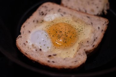 Birmingham usulü kızarmış yumurta. Ekmeğin içinde çırpılmış yumurta sıcak tavada pişiyor.