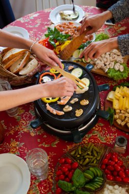 Raclette masası, rulet makinesi ve yemek malzemeleri. Farklı peynirlerle servis edilen İsviçre raketi, balık, salata, mantar, kırmızı biber, ekmek. self-servis partisi.