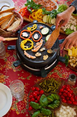 Raclette masası, rulet makinesi ve yemek malzemeleri. Farklı peynirlerle servis edilen İsviçre raketi, balık, salata, mantar, kırmızı biber, ekmek. self-servis partisi.