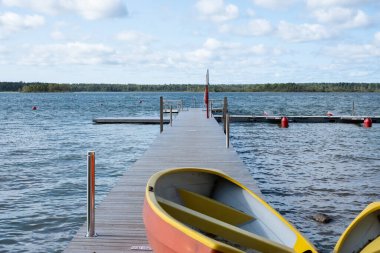 Büyük bir gölde renkli bir teknesi olan bir rıhtım ya da iskele. Kuzey Avrupa.