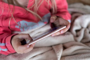 Akıllı telefon kullanan küçük bir çocuk. Evde cep telefonuyla oyun oynayan küçük bir kızın elleri.