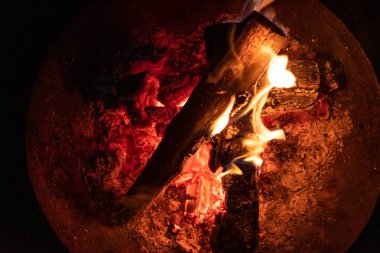 Siyah arka planda yakacak odun yakmak. Alevler içinde sıcak, yuvarlak bir şöminenin yakın çekimi.