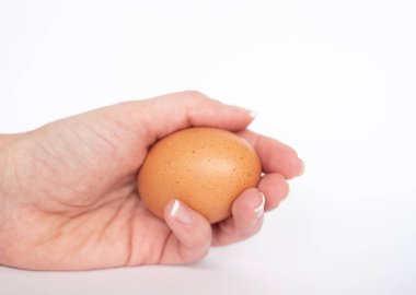 Beyaz arka planda dişi elinde doğal kahverengi yumurta. Kahvaltılık yemek. Haşlanmış yumurta..