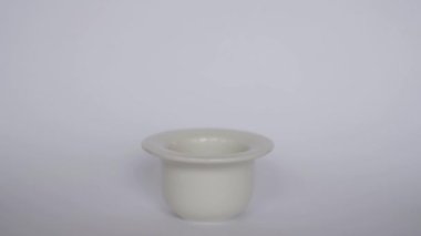 Doğal kahverengi yumurtayı beyaz arka planda basit bir beyaz yumurta kabına yerleştirir. Kahvaltılık yemek. Minimalist doğal Paskalya teması.