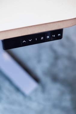 Uzaktan kumandasında yukarı, aşağı ve hafıza düğmeleri olan ayarlanabilir ofis masası. Akıllı boy ayarlanabilir masa ya da ayakta duran masa. Modern ofis aletleri ve mobilyalar. Ergonomik çalışma istasyonu.