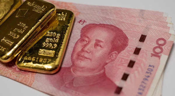 Gold bullion bars and Chinese Yuan renminbi banknotes, paper money and currency. Bank of China reserves. Gold backed Chinese yuan. Financial system of China.