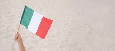 Çocuğun elinde İtalyan bayrağı sallıyor. Kum zemininde İtalya 'nın küçük bayrağı. Boş kopyalama alanı.