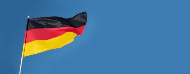 Alman bayrağı rüzgarda dalgalanıyor. Mavi gökyüzü arka planında Almanya bayrağı.