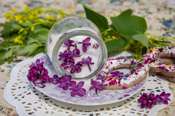 Flores de lila caramelizadas en un frasco de vidrio y galletas —  Fotos de Stock