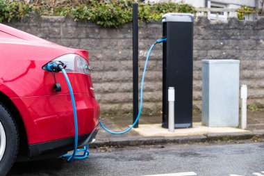 Cardiff, Wales, İngiltere - 14 Şubat 2021: Kırmızı Tesla, elektrikli araba (EV), Cardiff Konseyi tarafından sağlanan bir iskan caddesinde şarj noktası kullanıyor