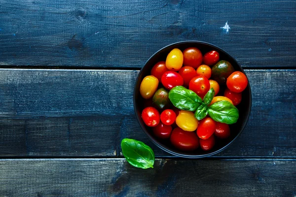 Tomatoes in black bowl — Stock Photo, Image