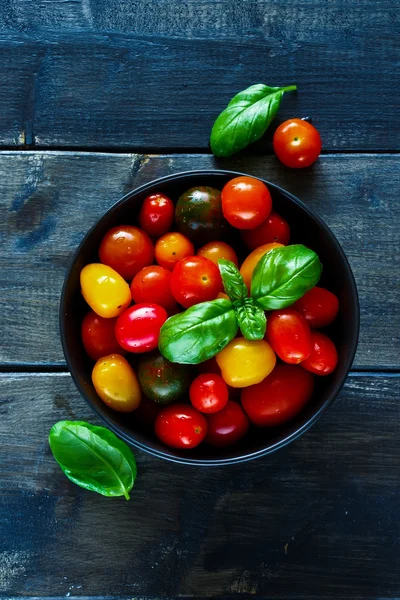 Tomatoes in black bowl — Stock Photo, Image