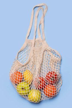 Mavi arka planda meyve ve sebze dolu market poşeti. 