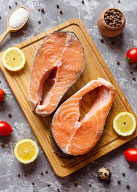 Baharatlı somon bifteği, limon pişirme tahta kesme arka planı.