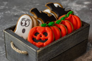 Cadılar bayramı için zencefilli kurabiye, hayalet ay, tabut, yarasa, gri taştan bir arka planda, tahta bir kutuda. 