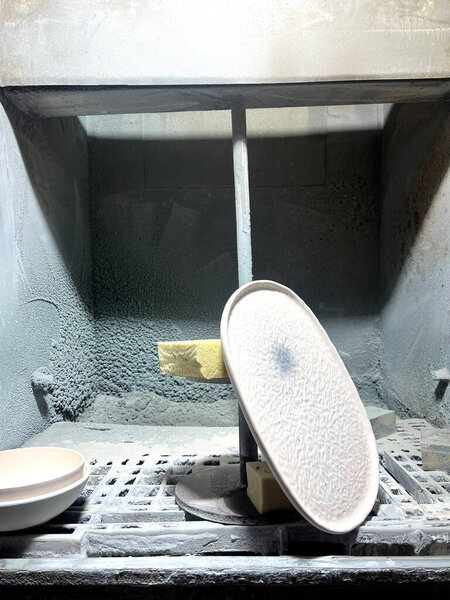 In a workshop, clay is shaped into ceramics as tools and materials surround the workspace, ready for production.