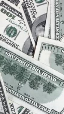Düz bir yüzeyde 100 dolarlık banknotlardan oluşan bir koleksiyon gösteriliyor. Para çerçeveler arasında farklı şekillerde istiflenmiş, detaylarını vurguluyor..