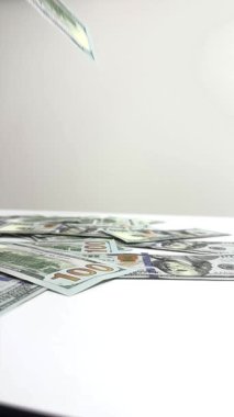 Nakit paralar parlak bir odadaki masaya düşer. Hareket, yüzeye çıkan ve yerleşen banknotları gösteriyor, para üzerinde görsel bir odak oluşturuyor..