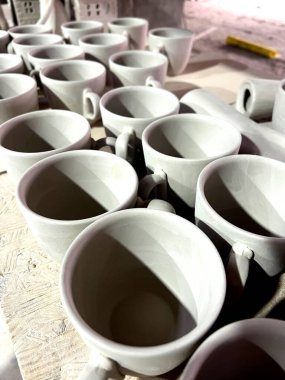 Gündüz vakti çömlek atölyesinde şekillendikten sonra kuruyan kilden yapılmış seramik bardaklar bir yüzeye dizilir..