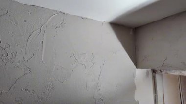Bir insan evdeki iç duvarın köşesine alçı yapıştırır. İş gün içinde halledilir. Bölgede görev için iyi ışıklandırma var..