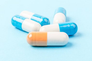 Mavi ve beyaz kapsüller ve turuncu beyaz kapsül hapları mavi arka planda. Uzayı kopyala Küresel sağlık hizmeti kavramı. Antibiyotik ilaç direnci. Antimikrobik kapsül hapları. İlaç endüstrisi..
