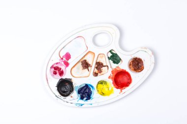 Beyaz arka planda boyaları olan bir palet, üst manzara. Kapat.