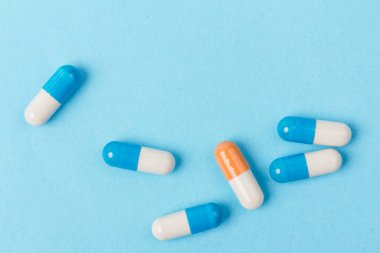 Mavi ve beyaz kapsüller ve turuncu beyaz kapsül hapları mavi arka planda. Uzayı kopyala Küresel sağlık hizmeti kavramı. Antibiyotik ilaç direnci. Antimikrobik kapsül hapları. İlaç endüstrisi..