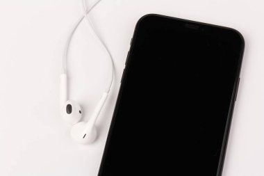 Kulaklık ve telefon beyaz arka planda. Müzik dinlemeye hazır mısın?