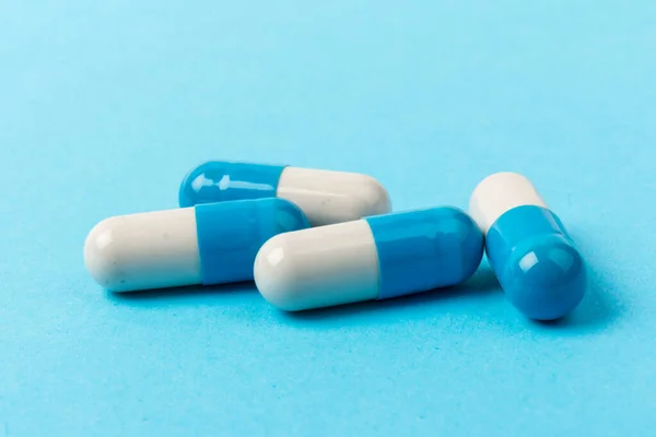 Blue and white capsules on blue background. Copy space. Global healthcare concept. Antibiotics drug resistance. Antimicrobial capsule pills. Pharmaceutical industry.