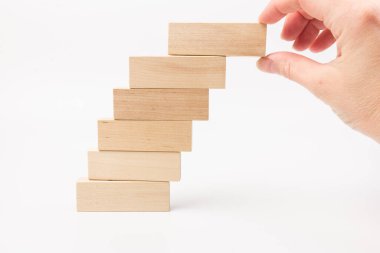 Beyaz arka planda tahta blokları olan merdivenler inşa eden bir kadın. Kariyer tanıtımı konsepti