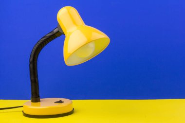 Sarı masa lambası sarı ve mavi arka planda izole edilmiş. Gündüz ve gece konsepti