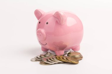 Beyaz arka planda para yığını olan domuz kumbarası, mesaj için yer. Finans, tasarruf. İş başarıya ve emeklilik konsepti için biriktirmeye