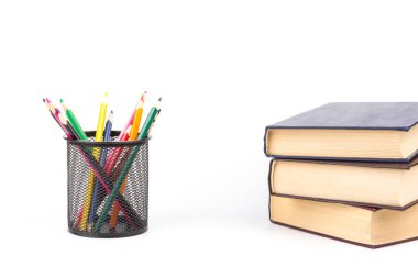 Tel örgü bardaktaki renkli kalemler, beyaz arkaplan, eğitim veya okula dönüş konsepti üzerine kitaplar.