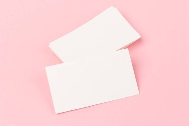 Pembe arkaplanda yakın planda beyaz kartvizit yığınları