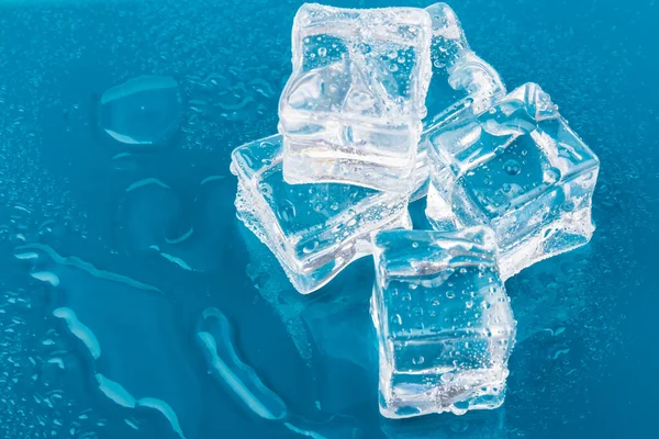 Pyramid of the melted ice cubes with drops.ice cubes and water drops close up on blue background