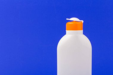 Mavi arka planda güneş kremi şişesi. Sağlık kavramları ve cilt bakımı