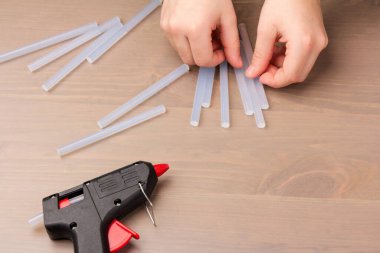 Sıcak eritilmiş silah, inşaat aletleri. Ahşap arka planda tutkal tabancası ve çubuklar.