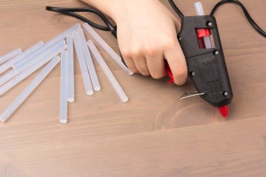 Sıcak eritilmiş silah, inşaat aletleri. Ahşap arka planda tutkal tabancası ve çubuklar.