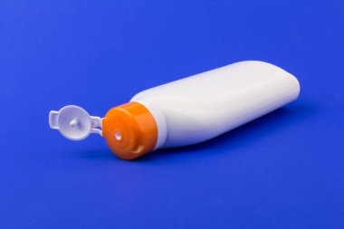 Mavi arka planda güneş kremi şişesi. Sağlık kavramları ve cilt bakımı