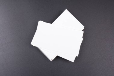 Siyah bir yüzeye yığılmış beyaz kartvizitler. Metin için boşluk