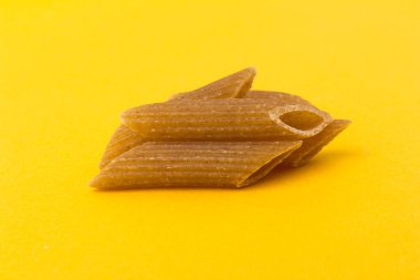 Sarı arka planda izole edilmiş sert buğday çeşitlerinden klasik makarna, yakın plan.