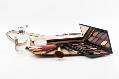 Makyaj malzemesi ve beyaz arka planda çanta olan bir şişe parfüm.