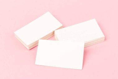 Pembe arkaplanda yakın planda beyaz kartvizit yığınları