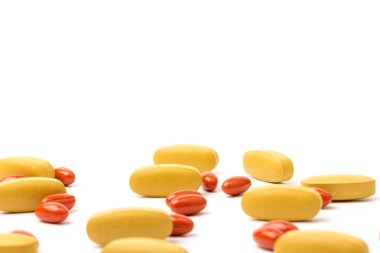Sarı ve turuncu Multivitamin ve sakatlama hapları, beyaz arka planda yakın planda besin desteği