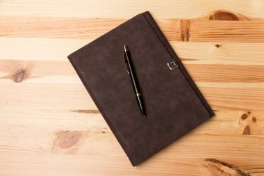 Tahta arka planda duran bir iş kalemi ve defter ile üst görünüm modelleme şablonu.