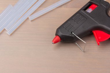 Sıcak eritilmiş silah, inşaat aletleri. Ahşap arka planda tutkal tabancası ve çubuklar.